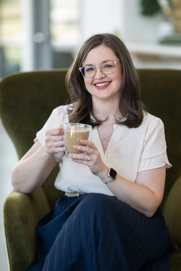 Allison Marx in a green chair, holding a coffee.