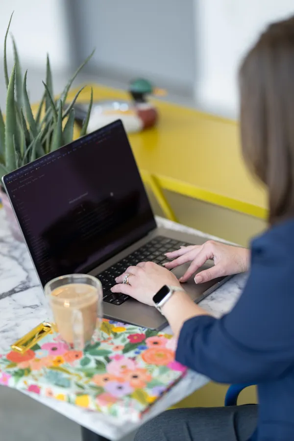 Working at a laptop, seen over the shoulder.
